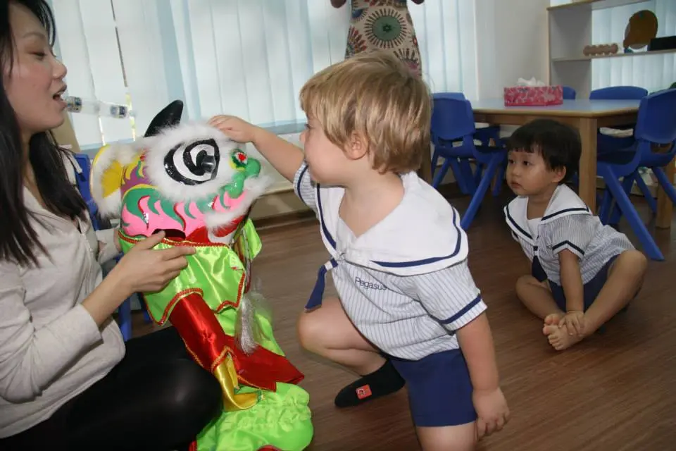 孩子们在成人的支持下触摸并观察舞狮狮头。