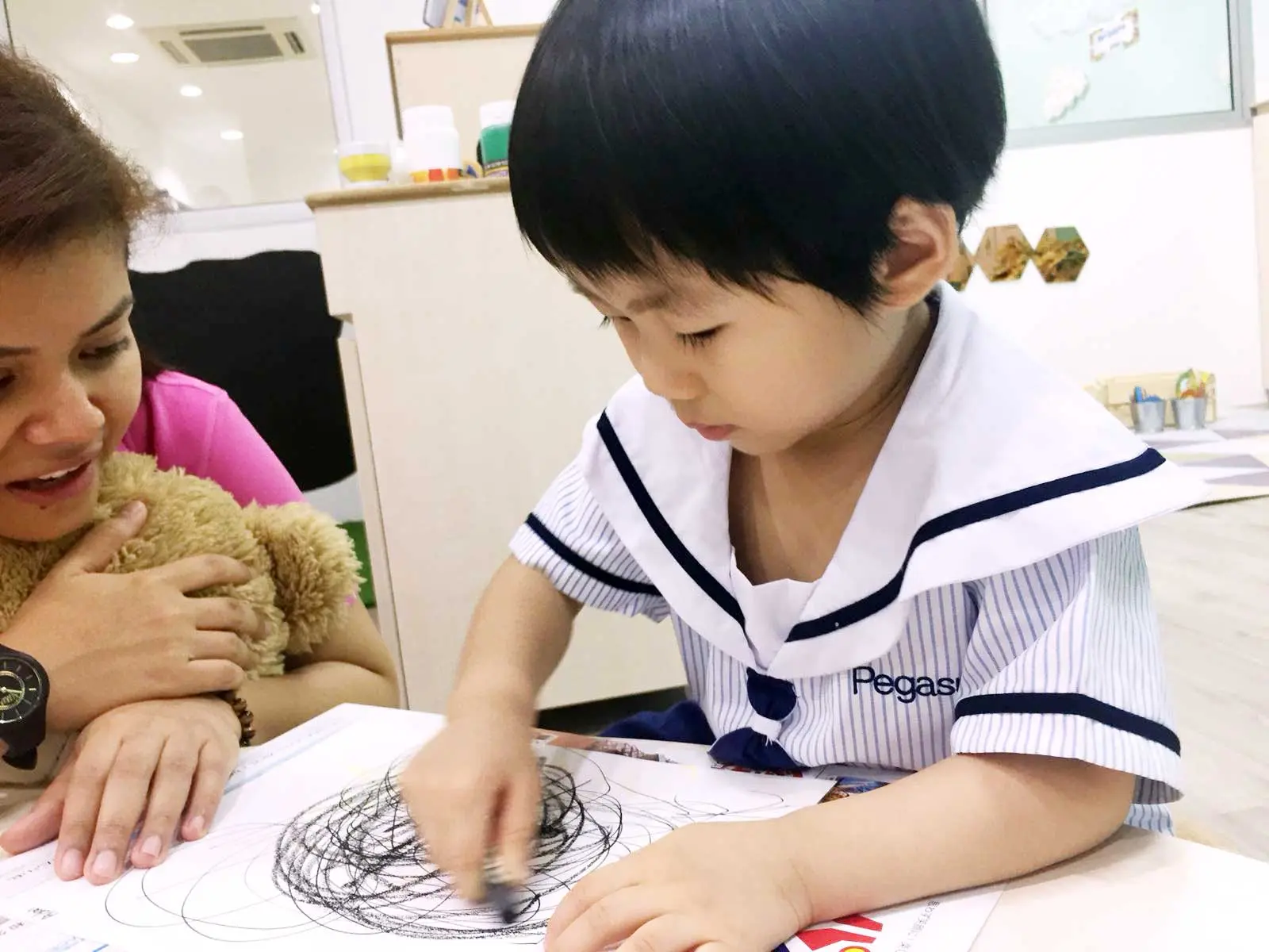 大人が見守るなか、大胆に丸をなぐり描きする子ども。