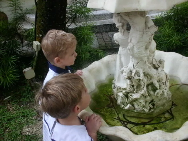 屋外の庭の噴水をじっくり見る子どもたち。