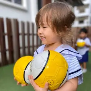 托儿班一的孩子在幼儿园活动中手持黄色足球
